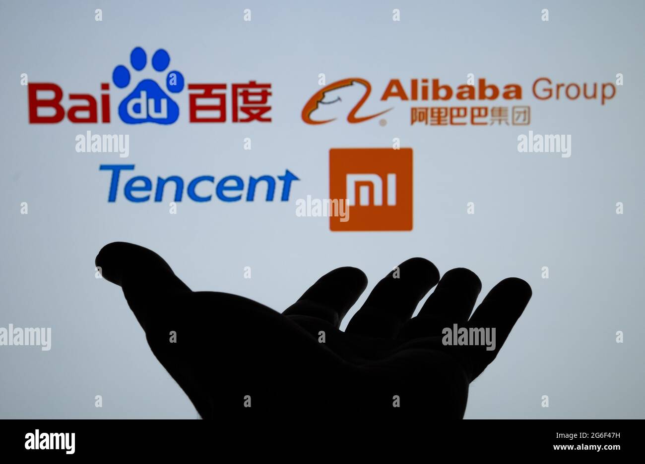 Silhouette of dark hand and blurred chinese Big Tech logos known as BATX Baidu Alibaba Tencent Xiaomi. Concept. Real photo, not a montage. Stafford, U Stock Photo