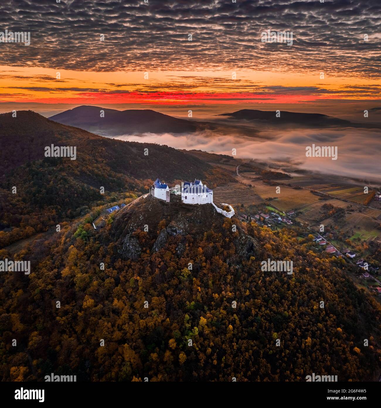 Fuzer, Hungary - Aerial view of the beautiful Castle of Fuzer with amazing colorful golden sunrise and clouds on an foggy autumn morning. The castle h Stock Photo