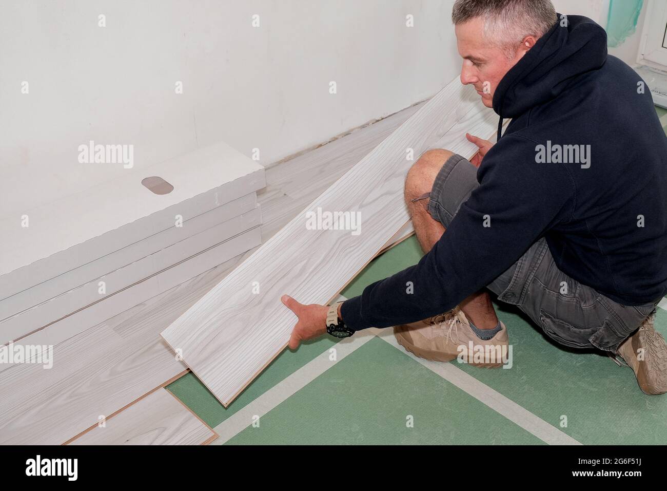 A worker who connects the laminate flooring during the renovation of the house. Stock Photo
