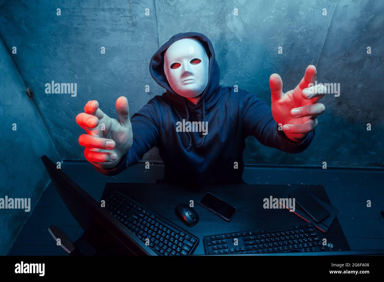 Anonymous hacker wearing face mask working on computer in dark room ...