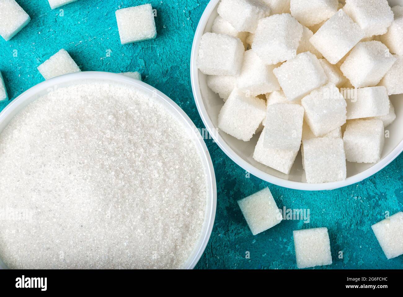 White sugar in bowls on blue textured background. Stock Photo