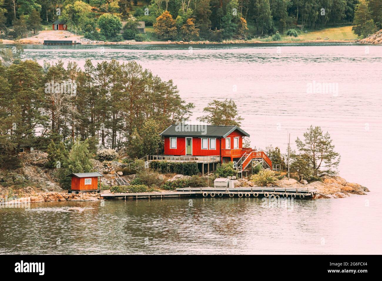 Sweden. Many Beautiful Red Swedish Wooden Log Cabin House On Rocky Island Coast In Summer. Lake