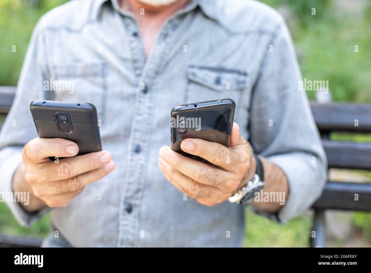 Old man compare two smartphones. Stock Photo