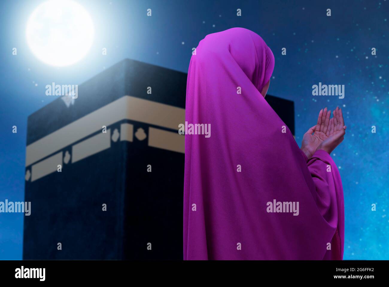Rear view of Asian Muslim woman in a veil standing and praying with ...