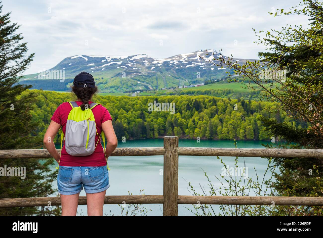 Young woman with Quechua backpack admiring view of lake Pavin in Auvergne Volcanic Regional Nature Park, France.  Active holidays in nature Stock Photo
