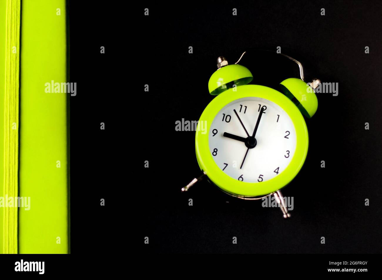 Light green alarm clock on a black background. Back to school. Time
