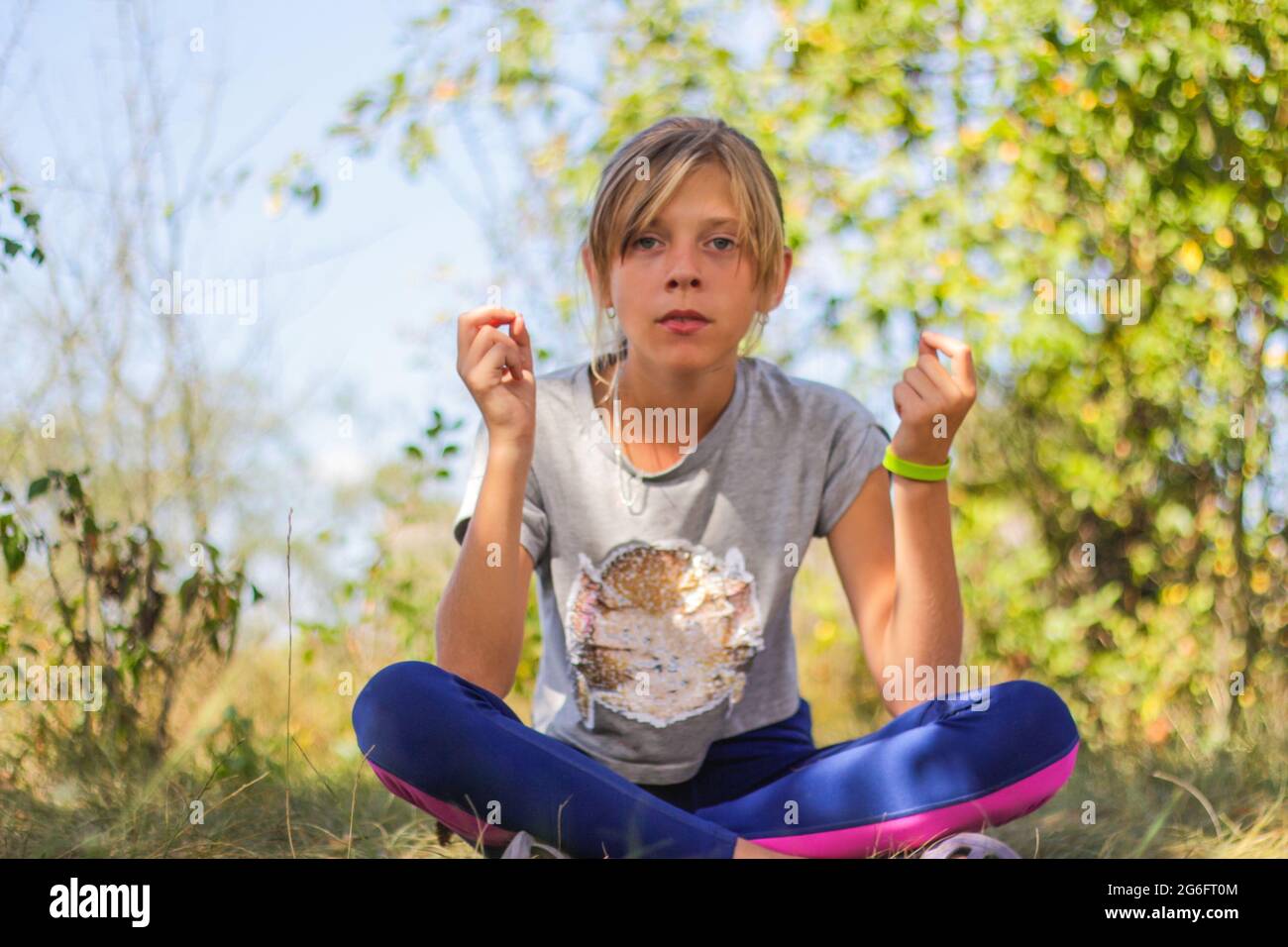 Defocus caucasian preteen girl practicing yoga in park, forest, outdoor, outside. Meditation and concentration. Wellness healthy lifestyle. Portrait o Stock Photo
