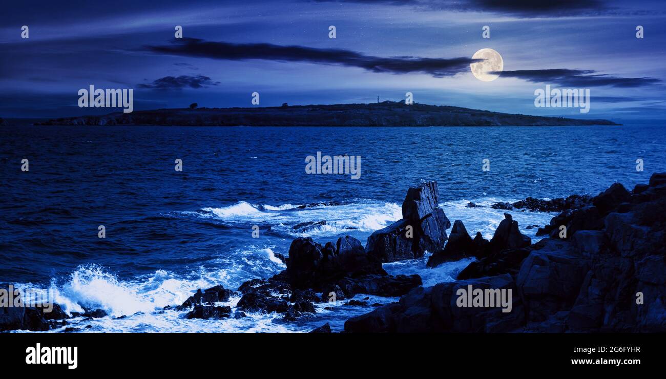 seascape at night. wonderful scenery with island and cliffs on the shore in full moon light. clouds above horizon. fantasy travel destination in summe Stock Photo