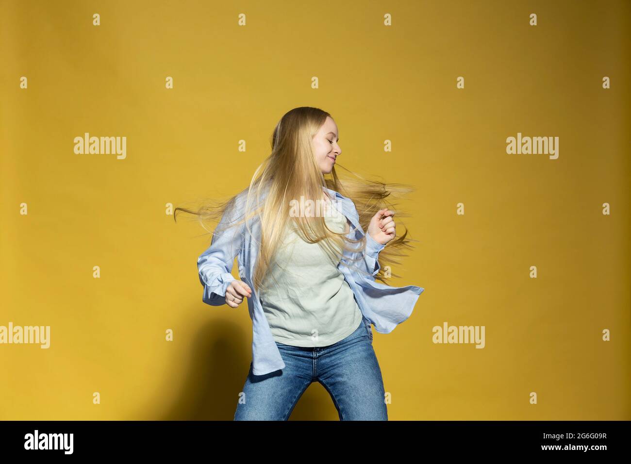 Carefree young woman dancing against yellow background Stock Photo - Alamy