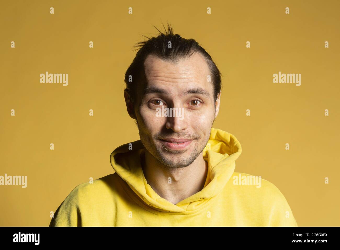 Portrait smiling man in hooded sweatshirt on yellow background Stock Photo