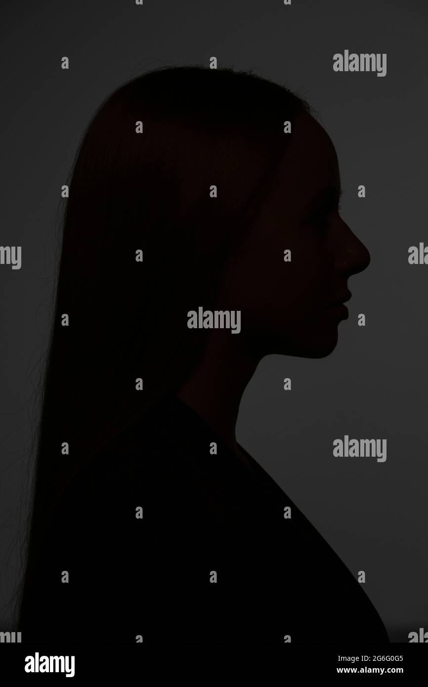 Dark silhouette young woman on black background Stock Photo