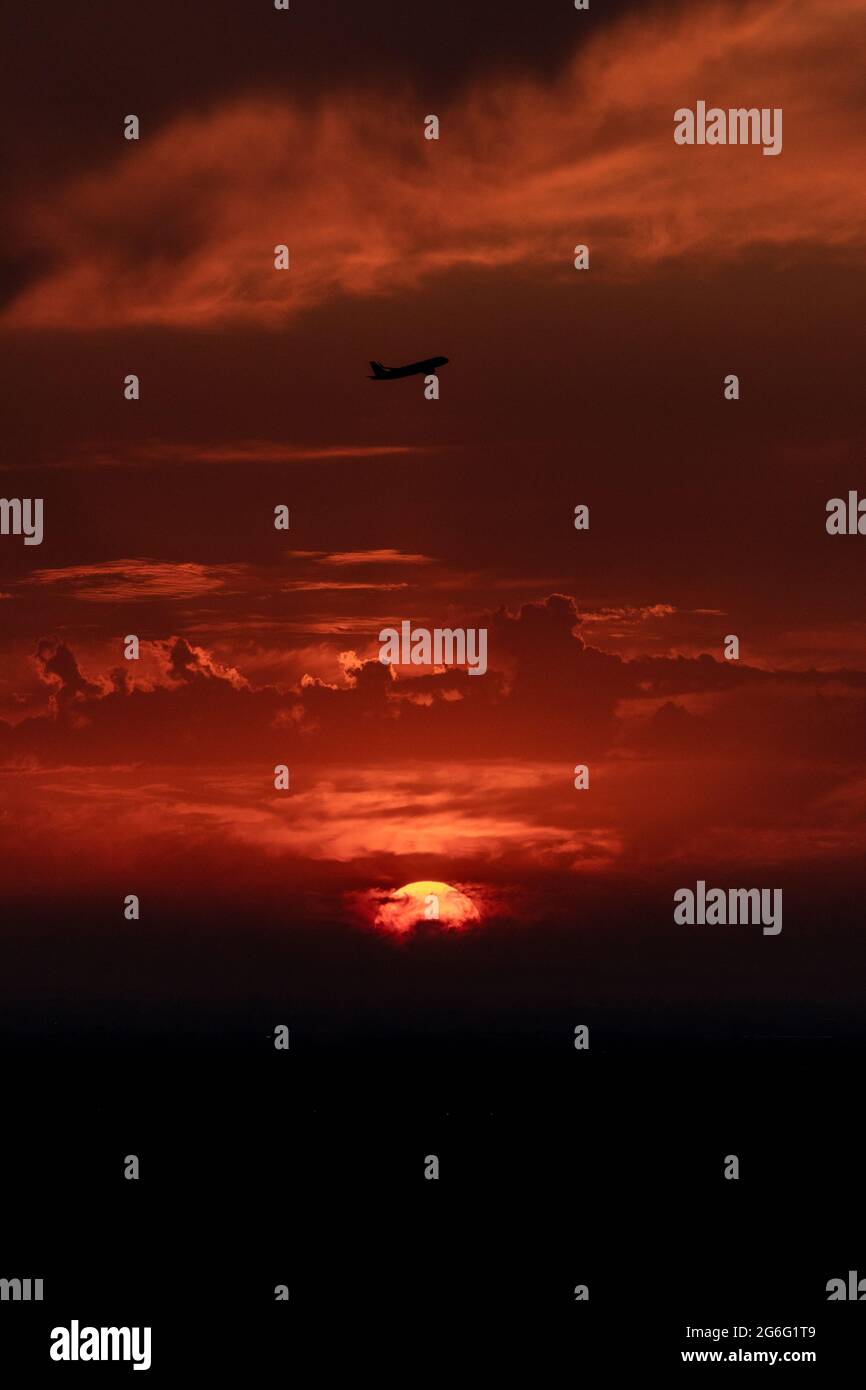 The plane takes off against the backdrop of a red sky and a beautiful ...
