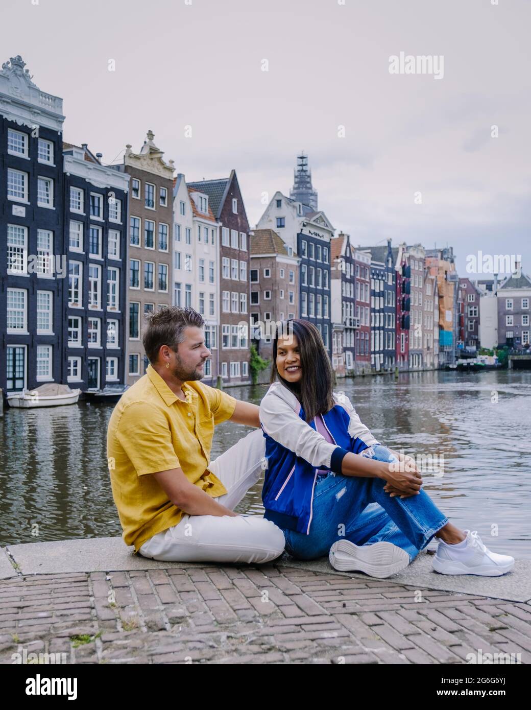 Amsterdam Netherlands, happy couple man and woman on a summer evening at the canals of Amsterdam. Man and woman mid age Asian girl and European men on city trip in Amsterdam Netherlands Stock Photo