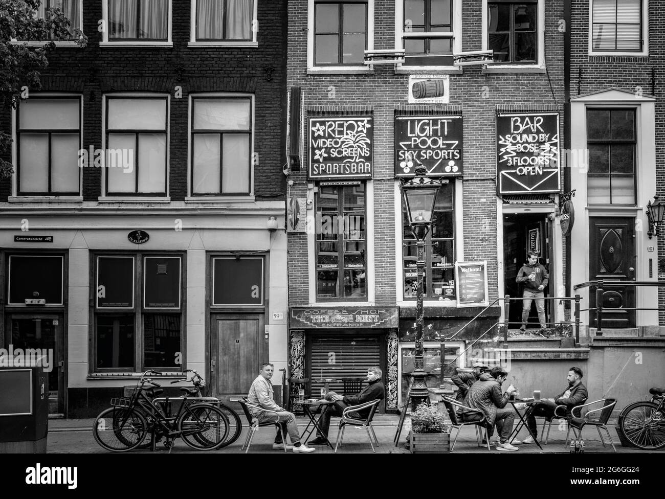 AMSTERDAM, NETHERLANDS. JUNE 06, 2021. Beautiful facades of the old dutch buildings. Restaurants on the street. Black and white photography. Stock Photo