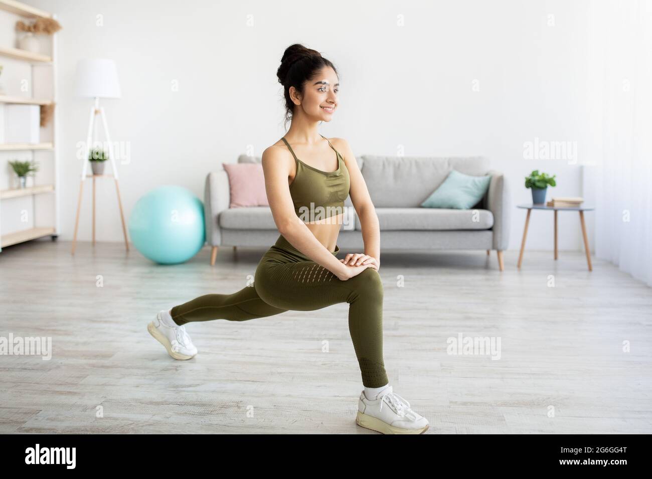 Pretty young Indian lady making lunge, doing strength exercises