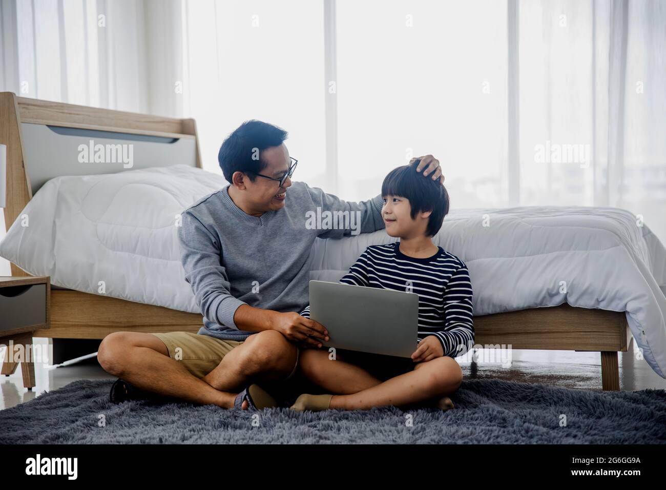 Dad or father talk with son working on laptop in bed room , family time ...