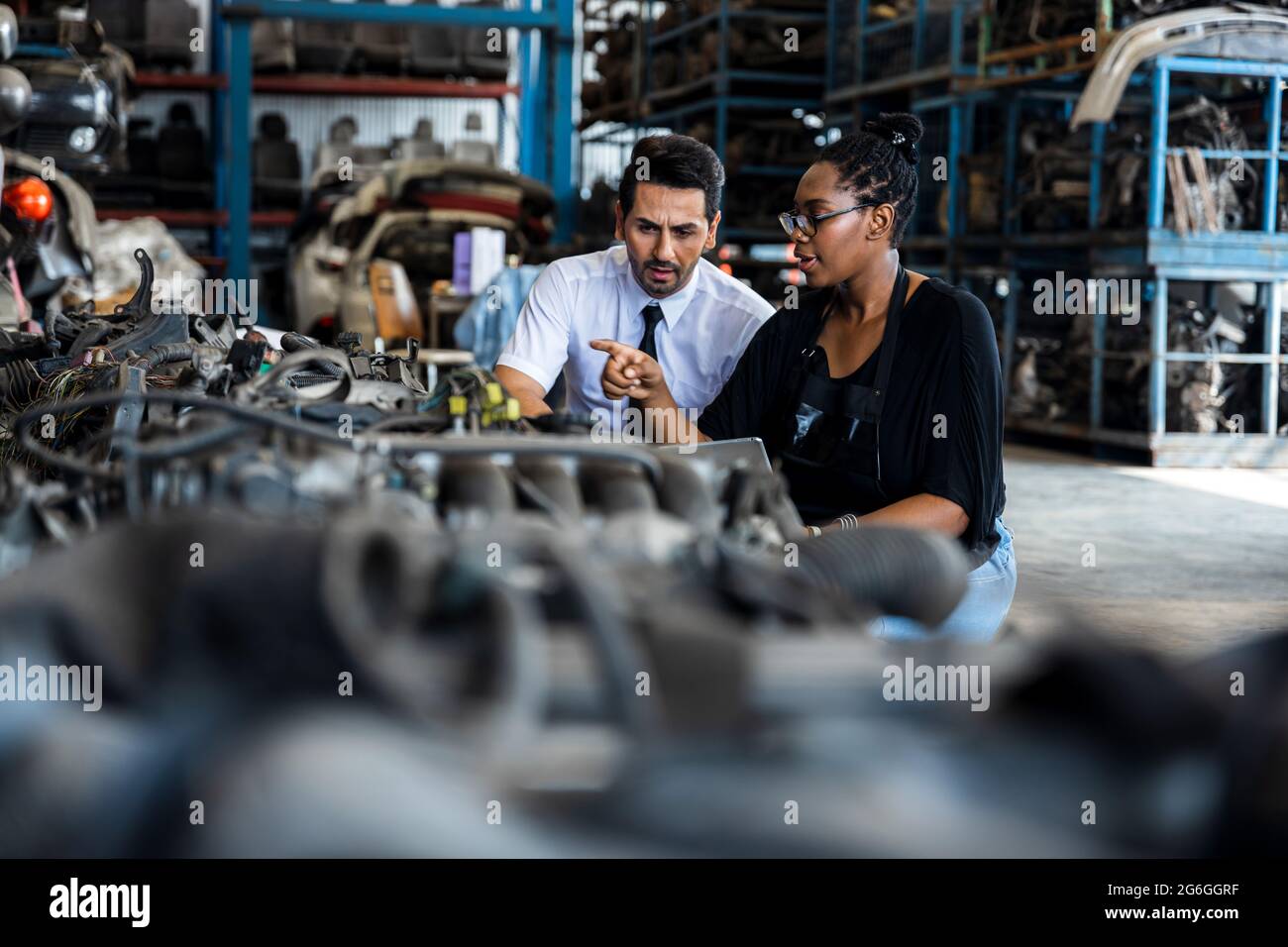 Old auto parts seller check on laptop and explain to customer or boss