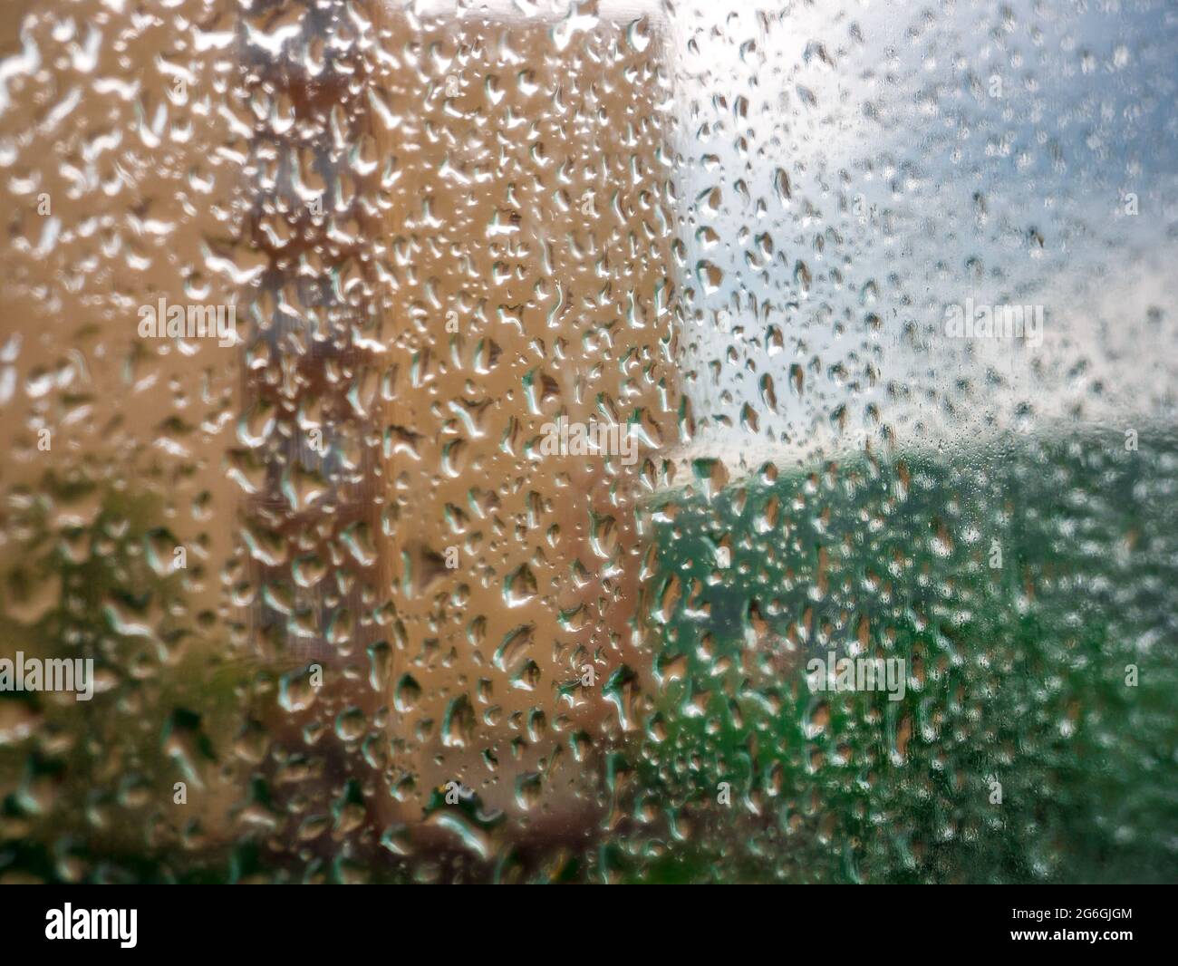 Rain drops on the window glass. Blurred background with house, greenery and  cloudy sky - selective focus Stock Photo - Alamy