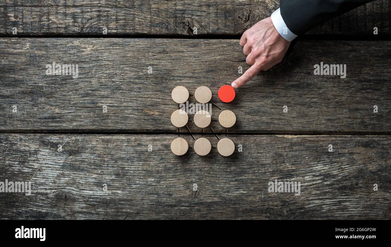 Social discrimation conceptual image - red wooden circle trying to fit in with a group of brown ones. Stock Photo