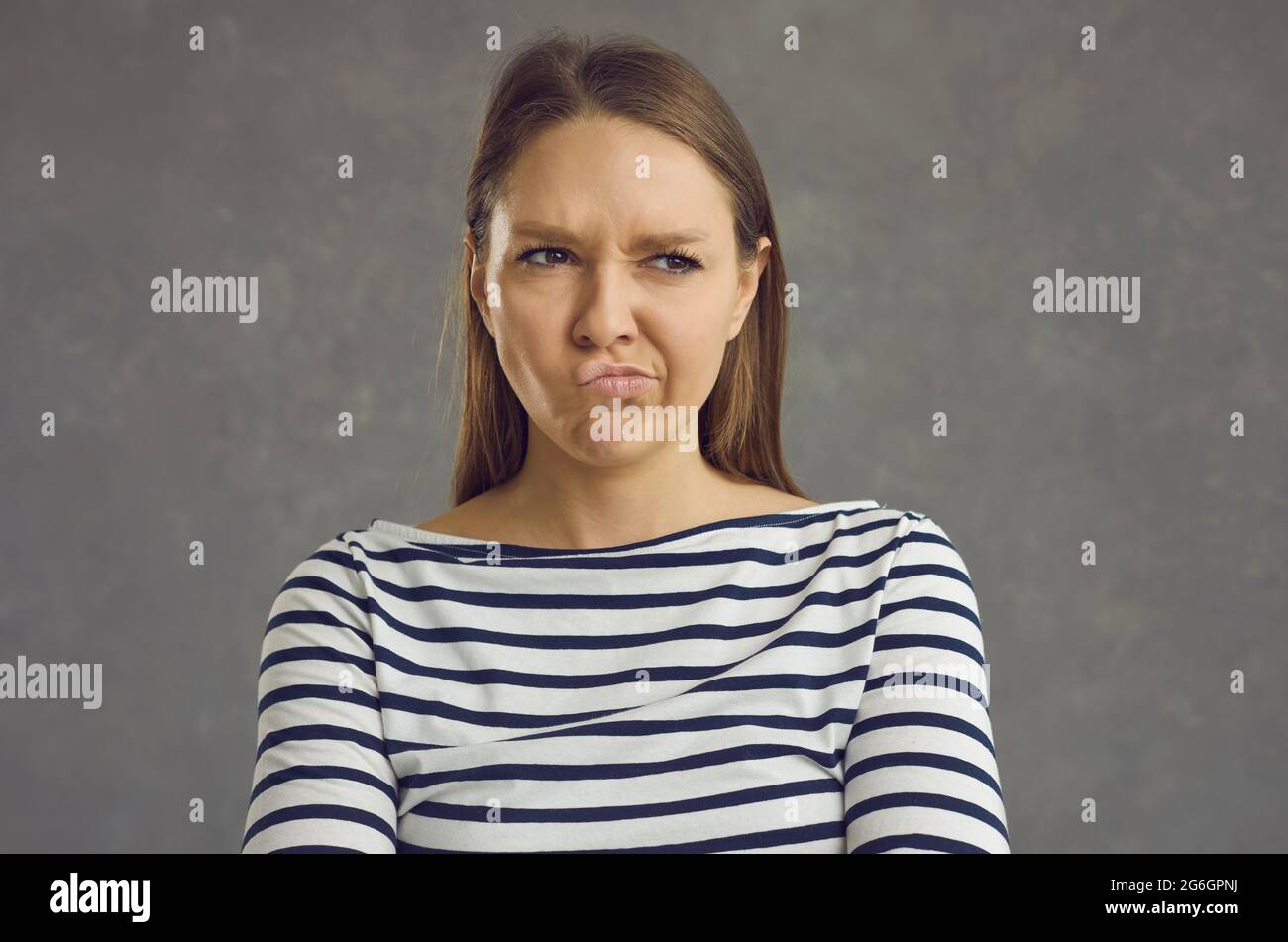 Portrait of young woman pouting lips and looking away with funny displeased face expression Stock Photo