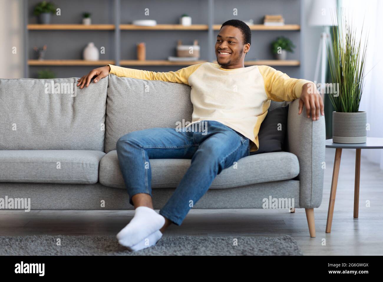 Joyful african american guy sitting on sofa at home Stock Photo - Alamy
