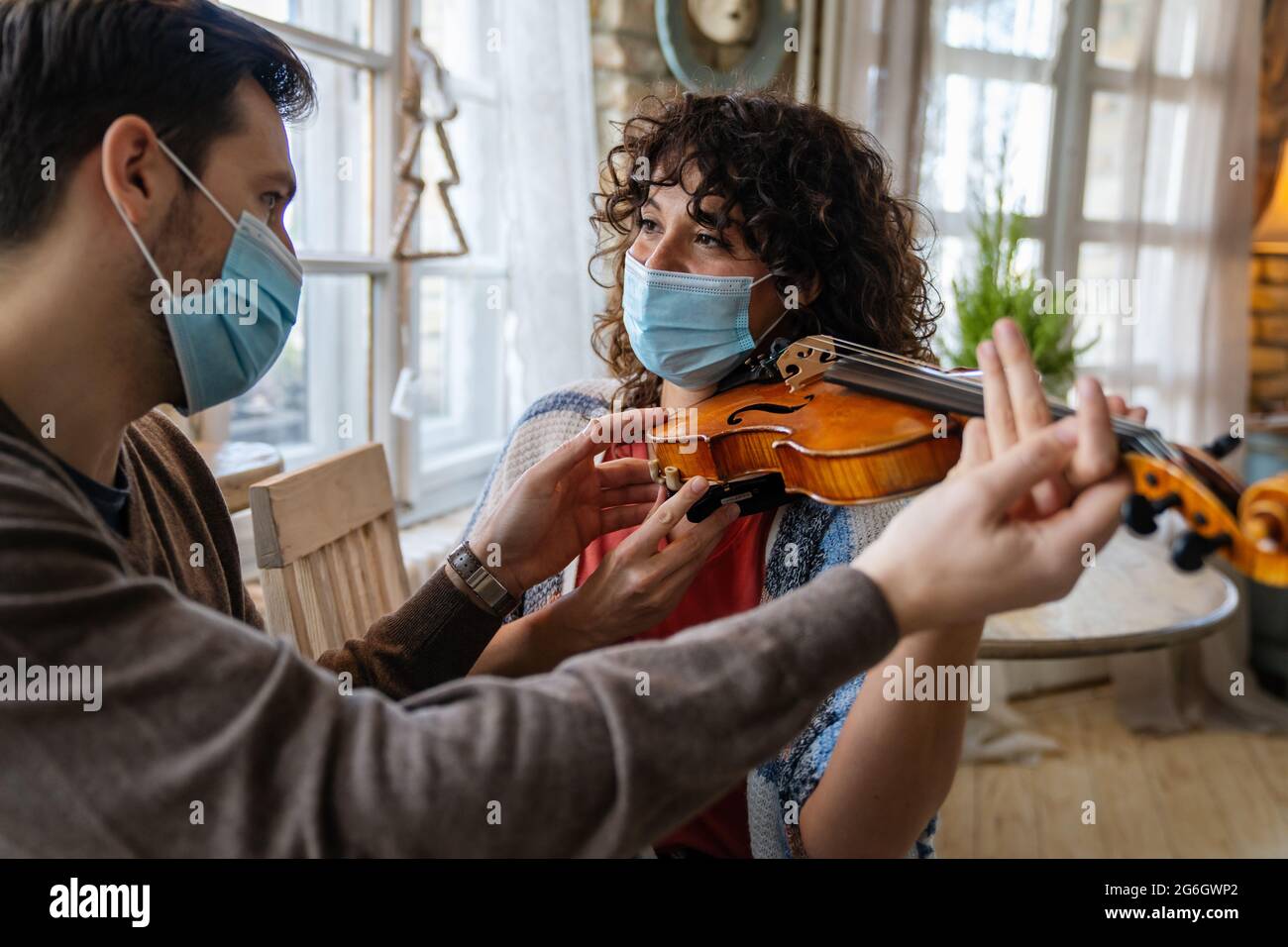Happy woman play violin under music teacher's instructions in mask ...