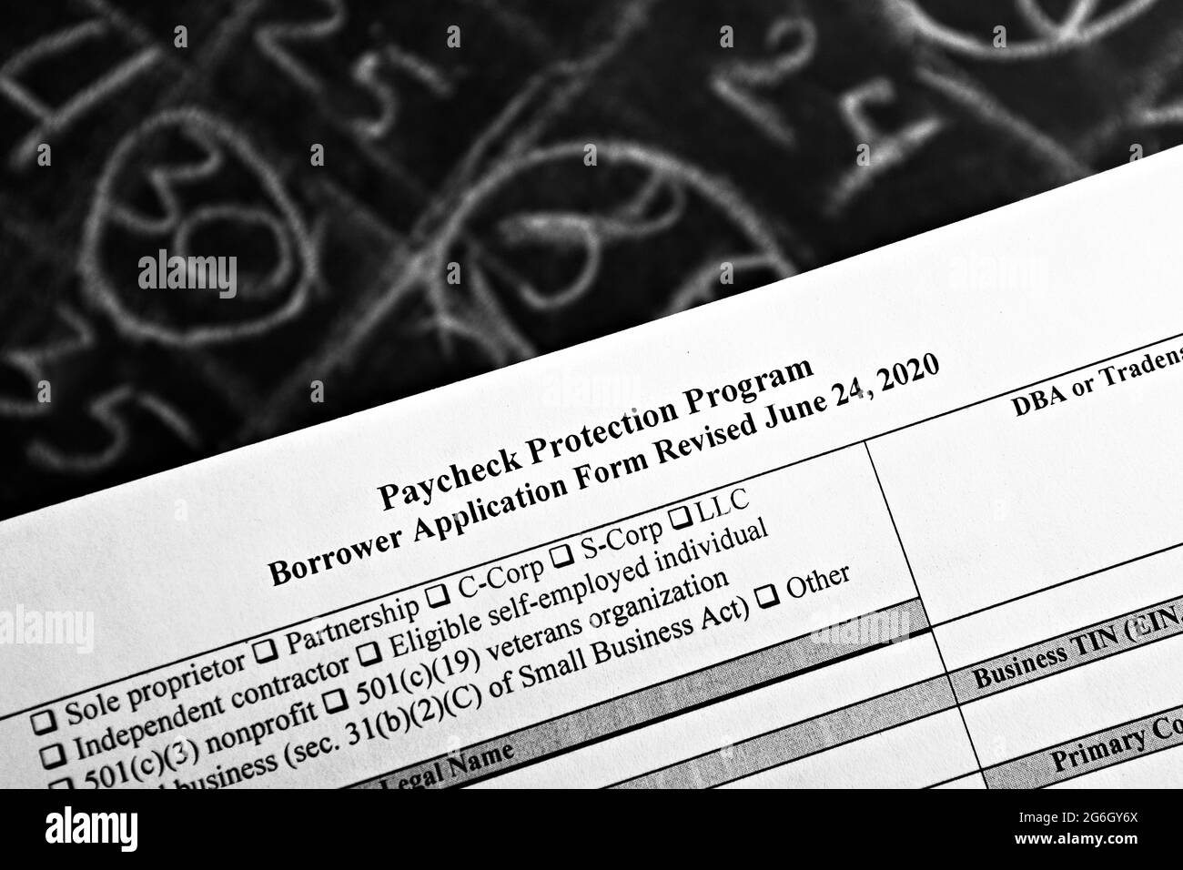 selective focus monochrome photo of paycheck protection program borrower application form revised, on a background of chalk board with numbers Stock Photo