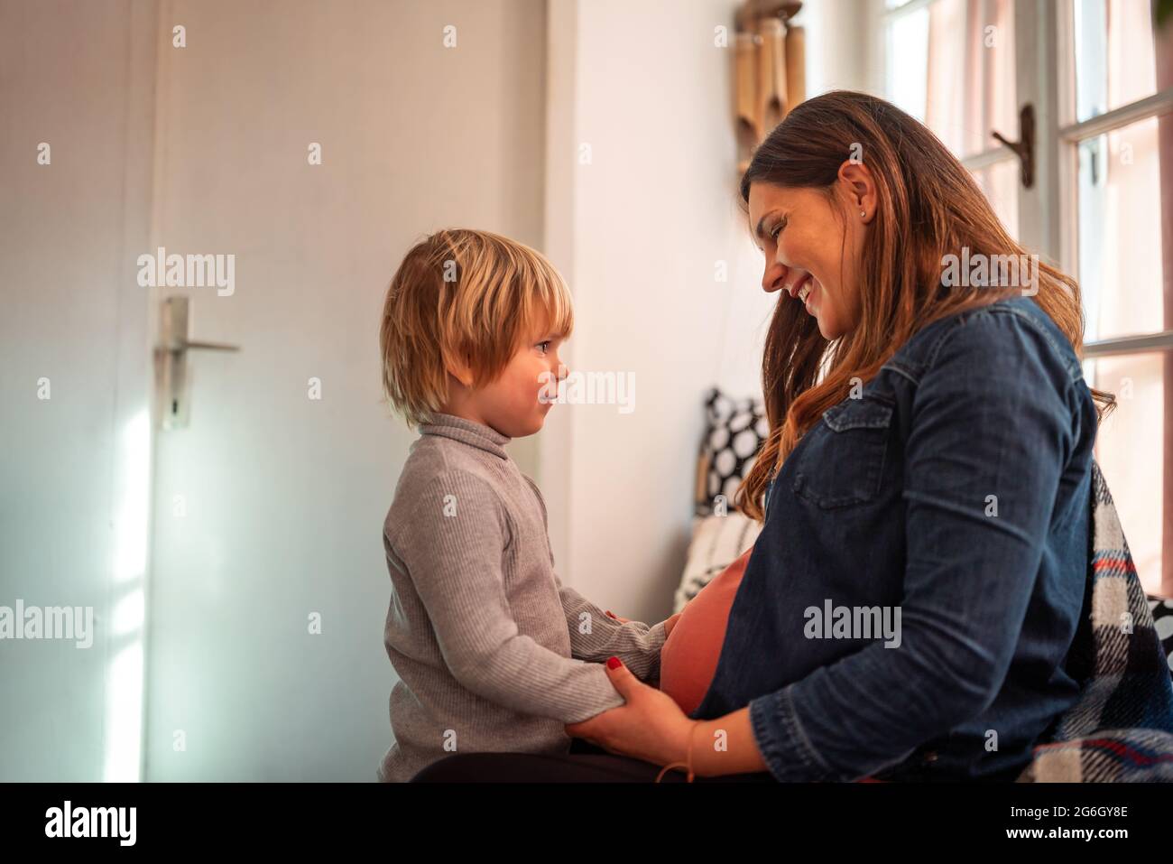 Happy child holding belly of pregnant woman. Family people love concept Stock Photo
