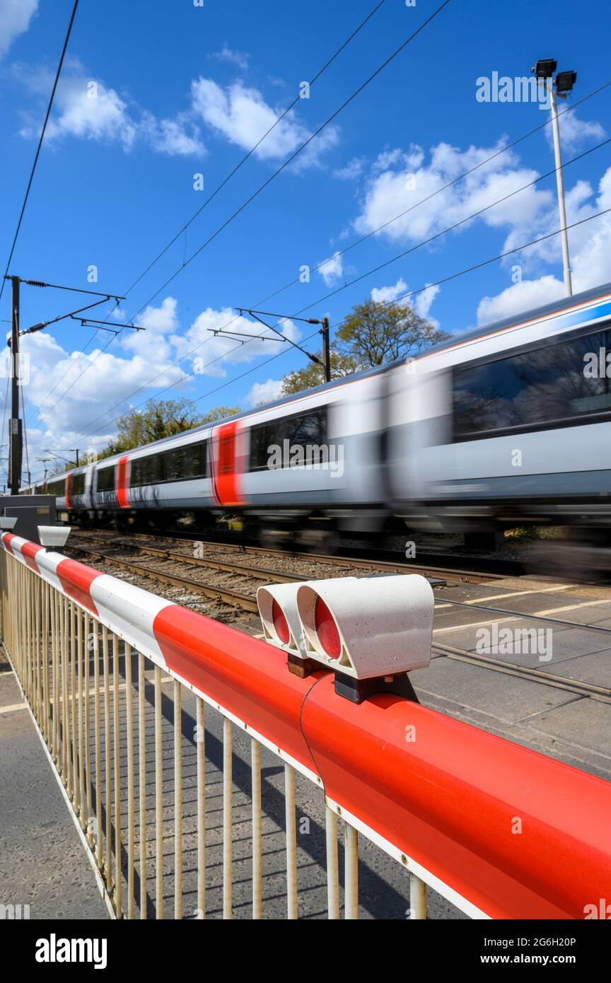 Train passing through a level crossing at speed in Essex, England. Stock Photo
