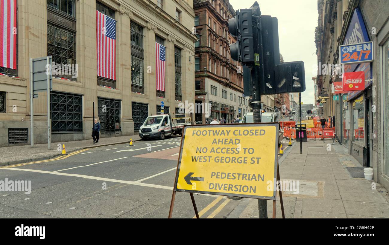Glasgow, Scotland, UK,  6th  July, 2021. UK  Weather: Final preparations for filming in st vincent street for the filming of the mystery blockbuster that has cost a fortune to prepare the city centre location along its length with cameras moving in tomorrow. American flags and presidential bunting on the new york architecture with the transformation of local shops into manhatten has led to speculation its the indiana jones film but the latest rumour is the new bat mobile will be running up the length of the street due to the size of the location. Credit: Gerard Ferry/Alamy Live News Stock Photo