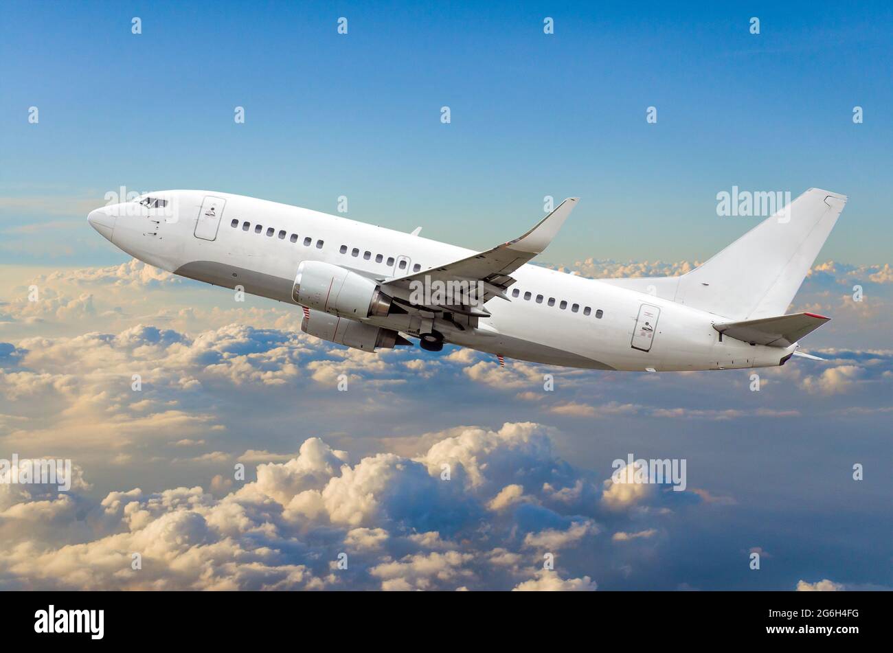 Passenger airplane flies in the sky gaining height above the clouds ...