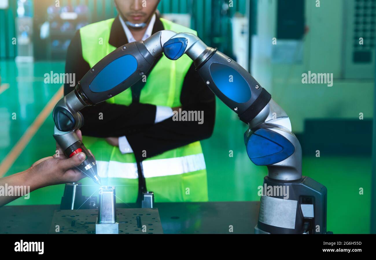 Asian engineers male female in Industrial wear hard hats in Industry manufacturing factory mechanical display interface arm robot manufacturing indust Stock Photo