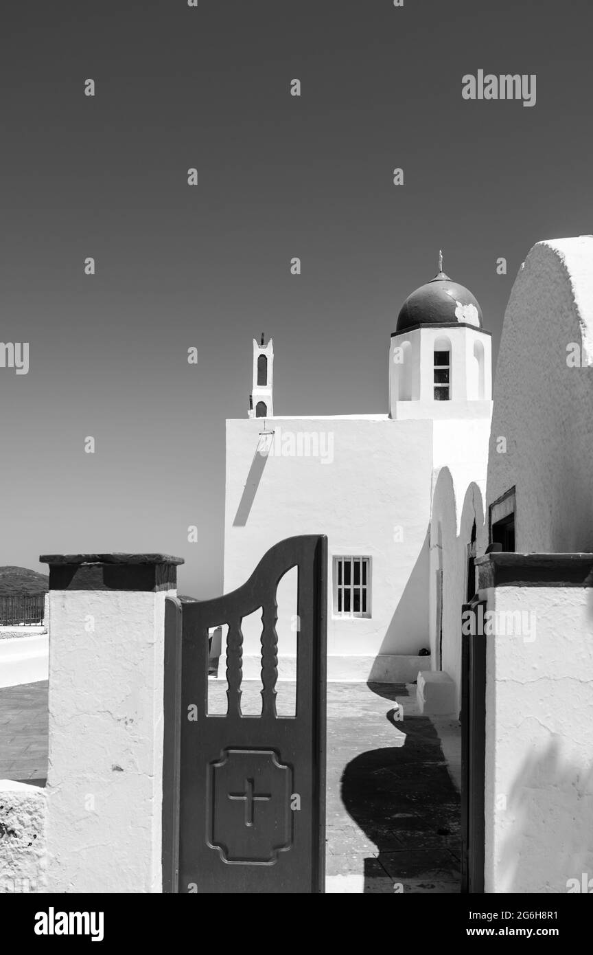 Small wooden door to traditional Greek Orthodox church on the island of Santorini. Opened gate. Sunny day. Black and white. Stock Photo