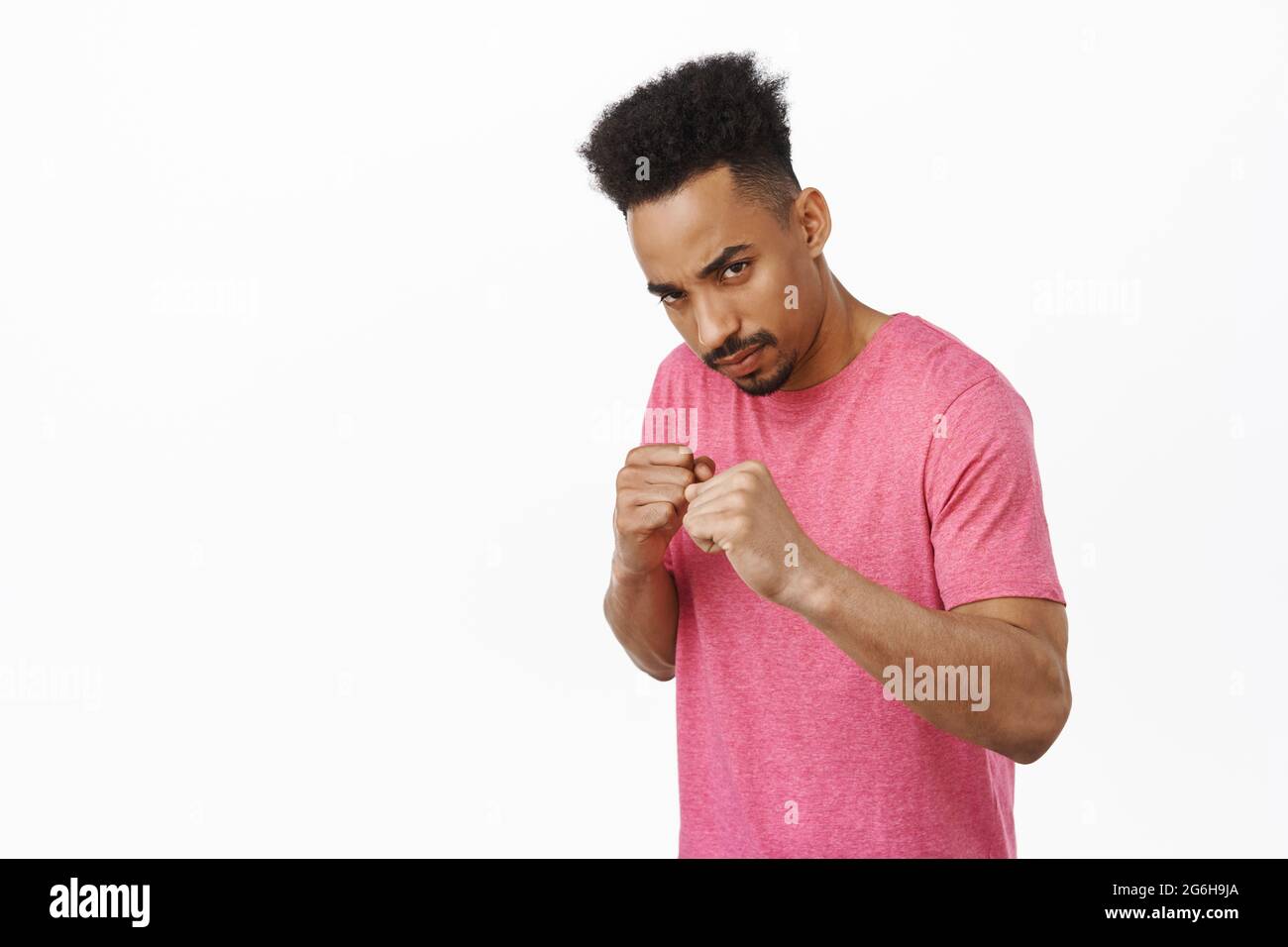 Serious and confident african american man ready to fight, raising clenched fists and furrow eyebrows, standing in defensive fighter pose, standing in Stock Photo