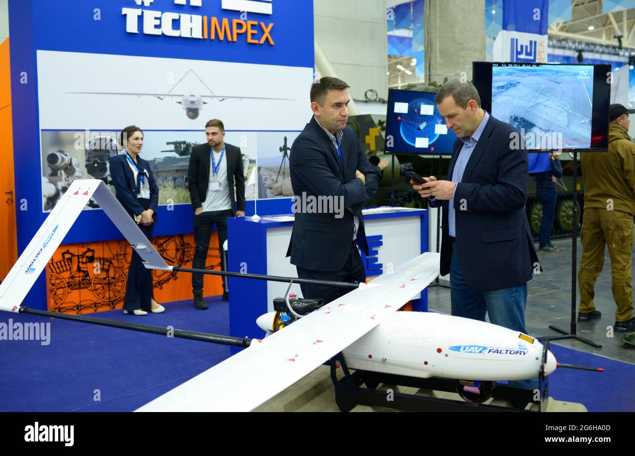 Two managers standing in front of the military unmanned aerial vehicles presented on a stand and discuss it. Exhibition Arms and Safety. October 08, 2 Stock Photo