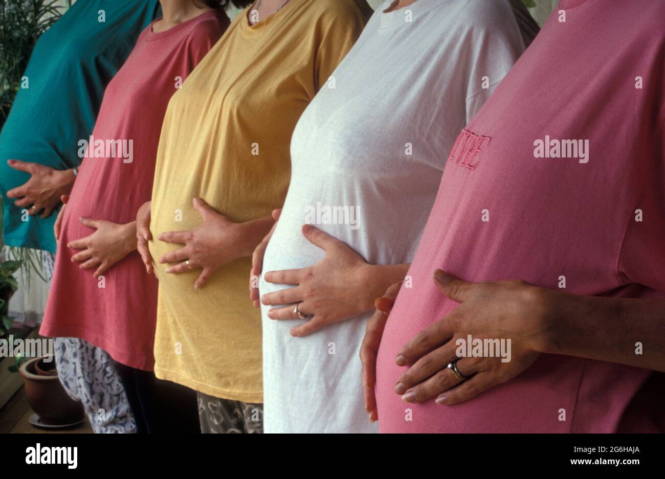 row of pregnant women, close up of hands on tummies Stock Photo