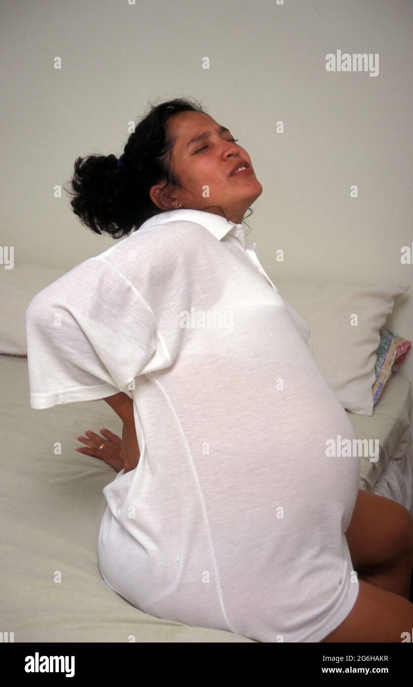 heavily pregnant hispanic woman in labour suffering from backache Stock Photo