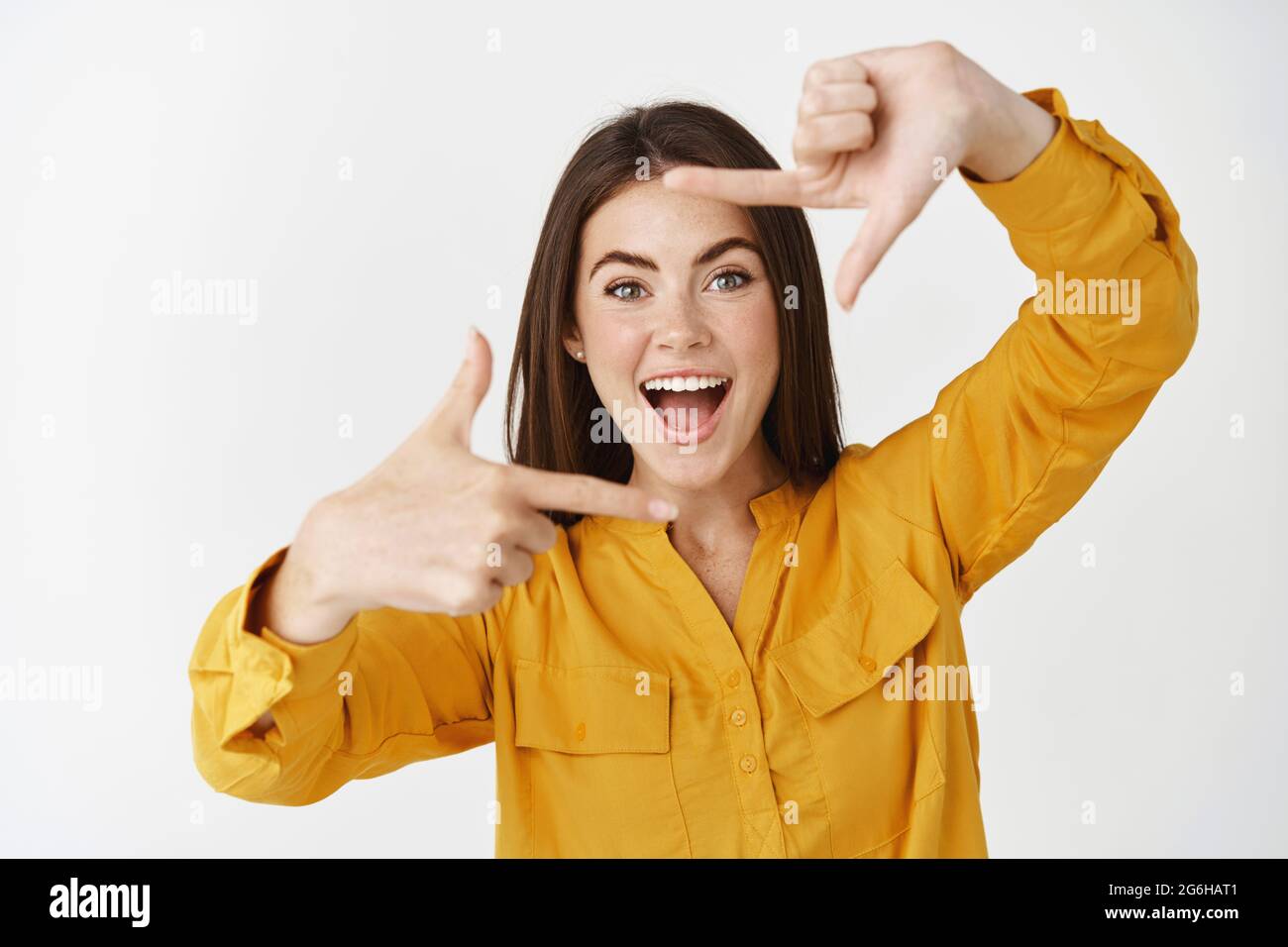 Happy young woman capturing moment, making hand frames camera gesture ...