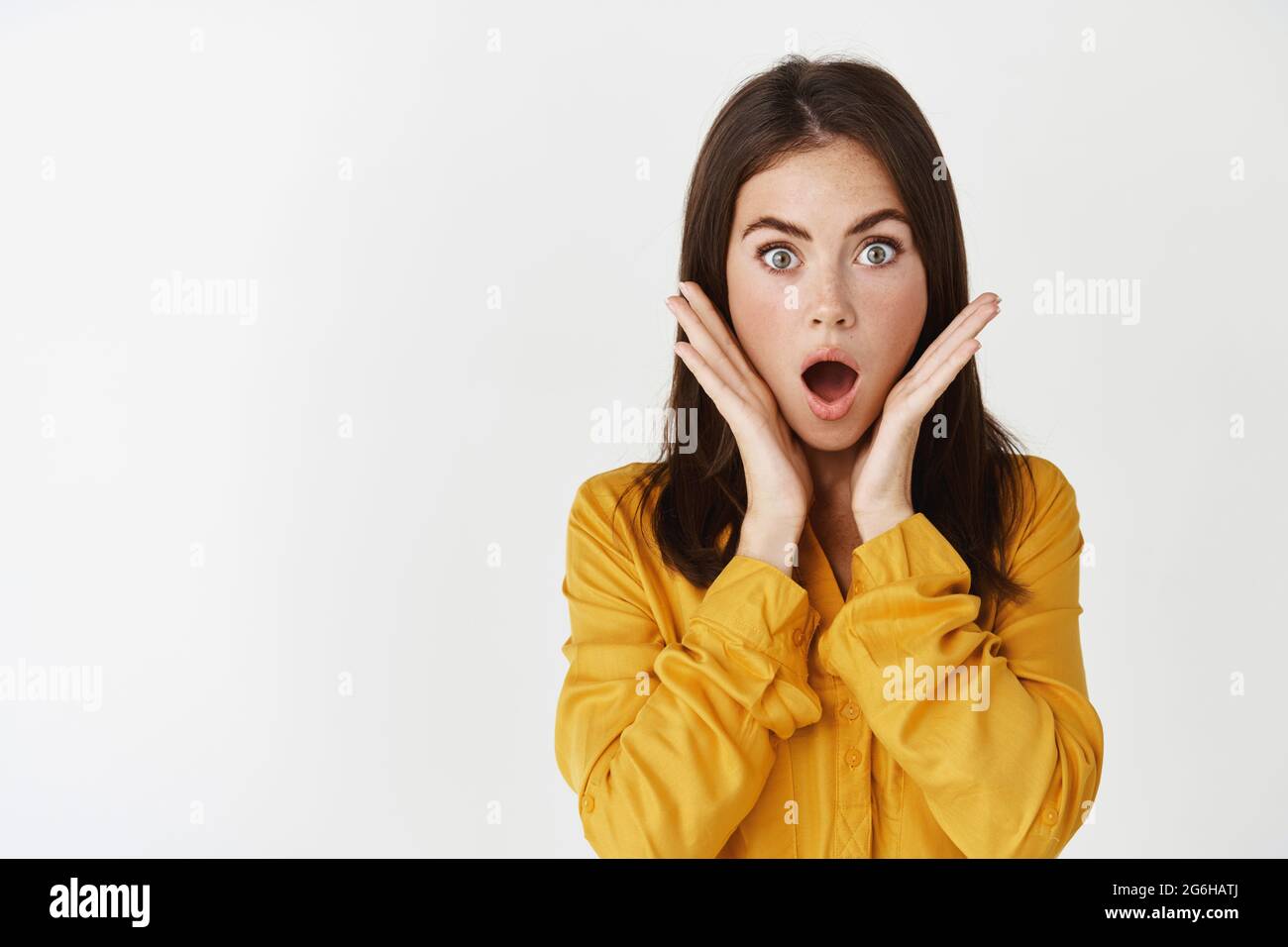 Close-up of shocked and speechless young woman gasping, staring at 