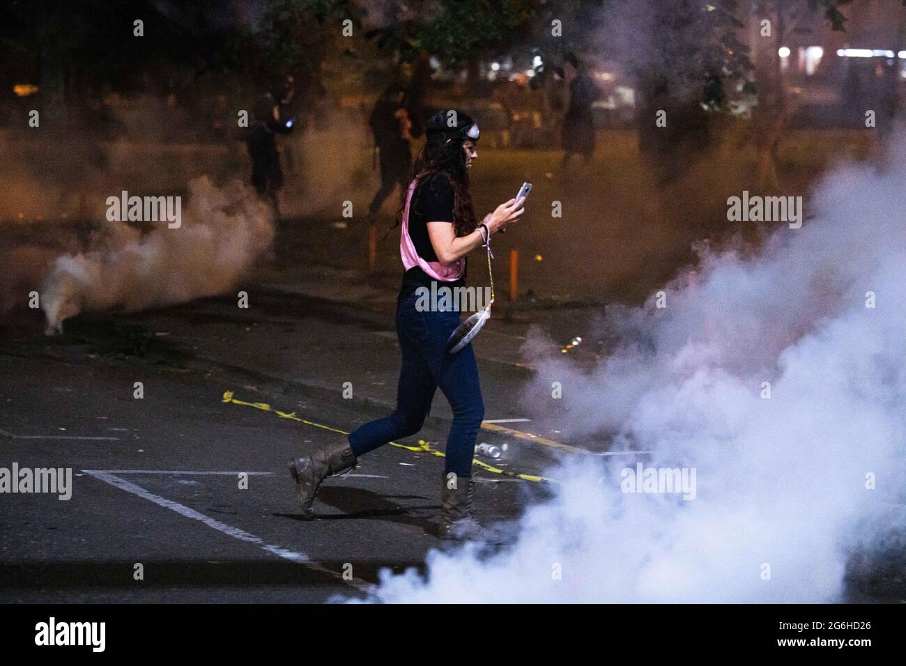 An activist runs through tear gas fired by federal agents outside the Mark O. Hatfield Courthouse. Portland, Oregon. July 4th, 2020  More than 750 DHS officers were dispatched to Portland over the summer of 2020 to protect federal property in a plan dubbed 'Operation Diligent Valor'. A DHS report claims protesters caused an estimated $1.6 million in damages to the federal courthouse while the cost of the operation exceeded $12 million. (Photo by Mathieu Lewis-Rolland/SIPA USA) Stock Photo