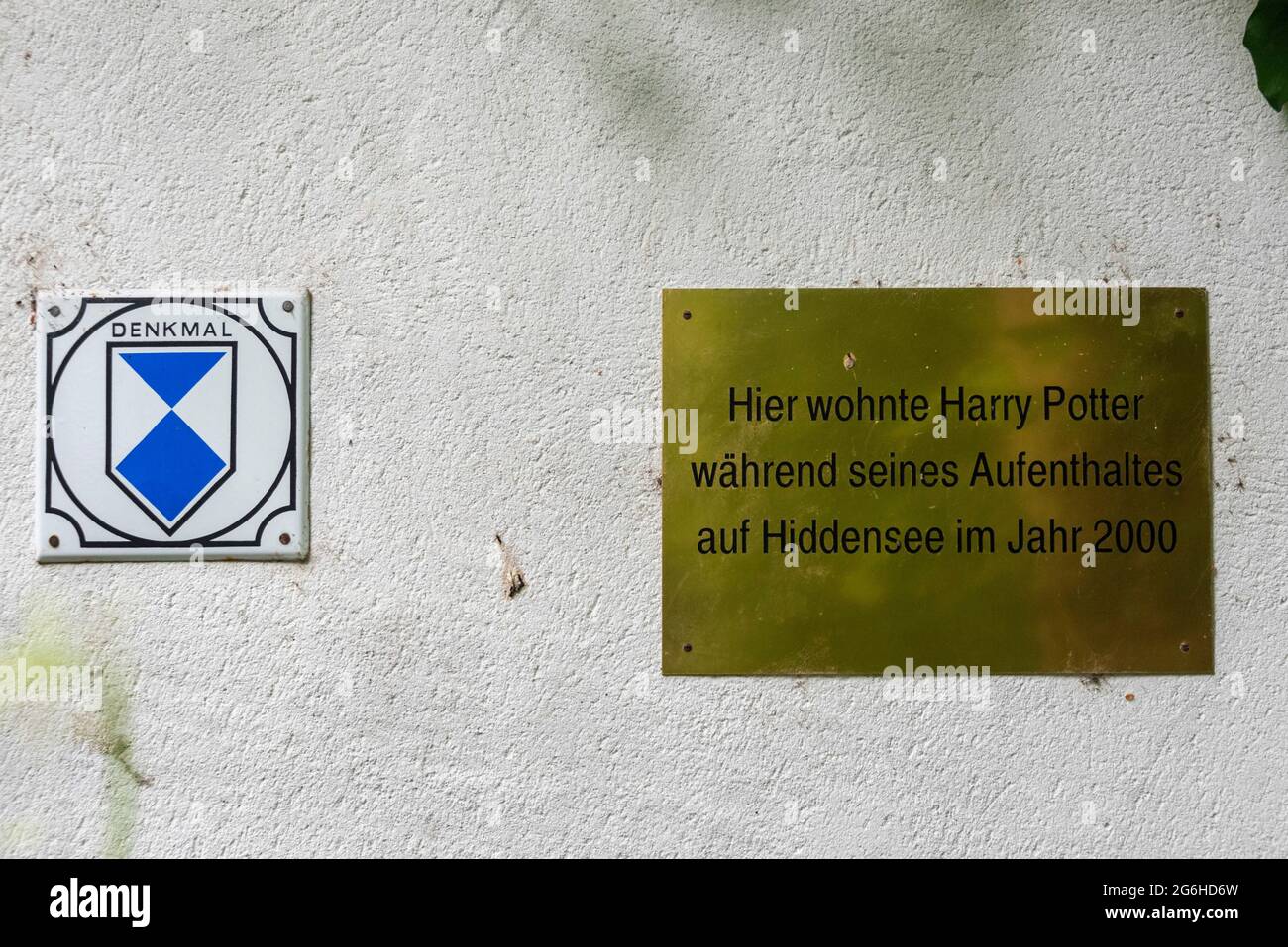 Hiddensee, Germany. 24th June, 2021. On a house in Kloster hangs a brass plaque with the inscription: "Harry Potter lived here during his stay on Hiddensee in 2000". Next to it is the sign for listed buildings. Credit: Stephan Schulz/dpa-Zentralbild/ZB/dpa/Alamy Live News Stock Photo