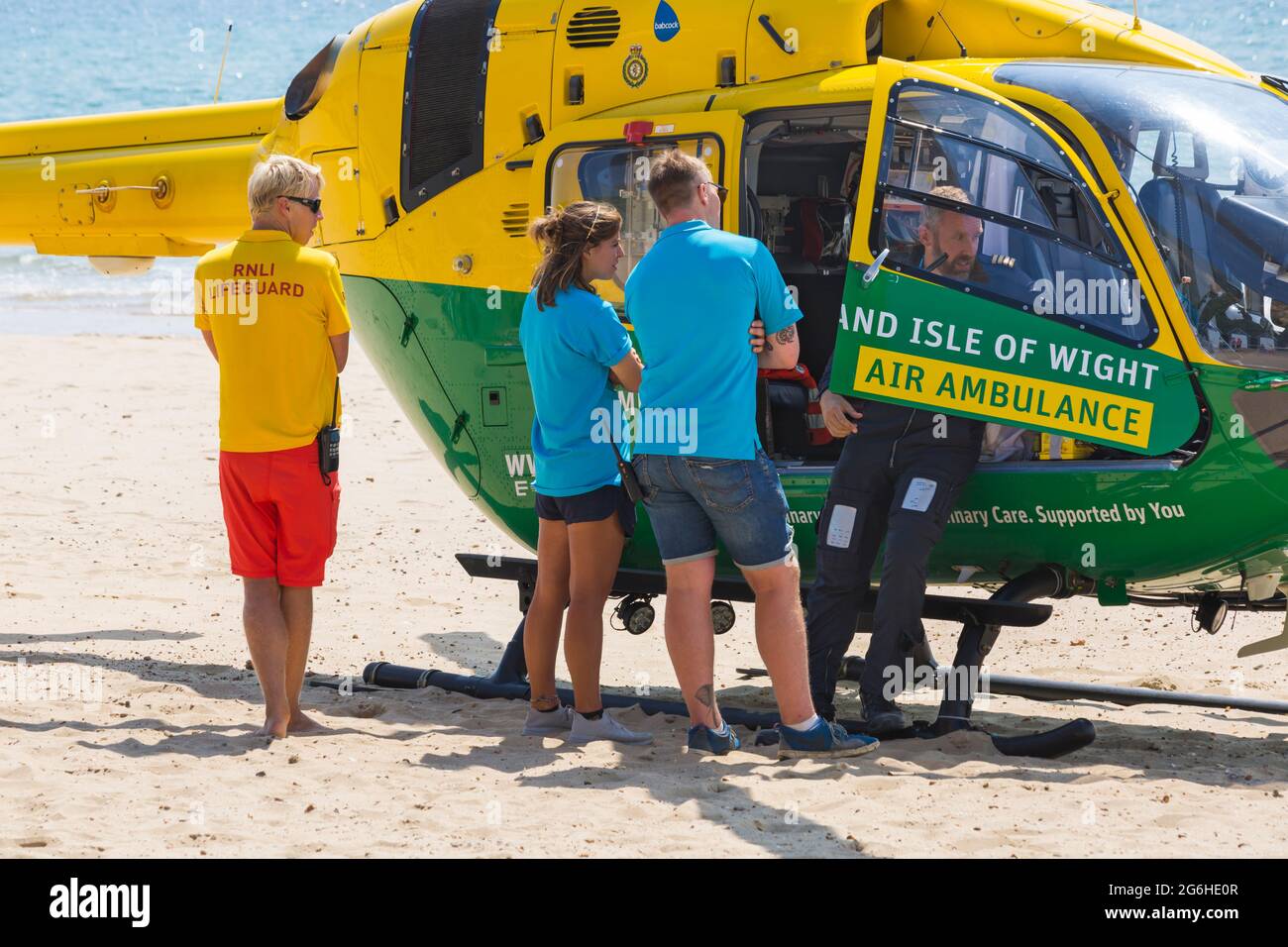 RNLI Lifeguard with Hampshire & Isle Of Wight Air Ambulance landed on Alum Chine beach to attend medical incident at Bournemouth, Dorset UK in July Stock Photo