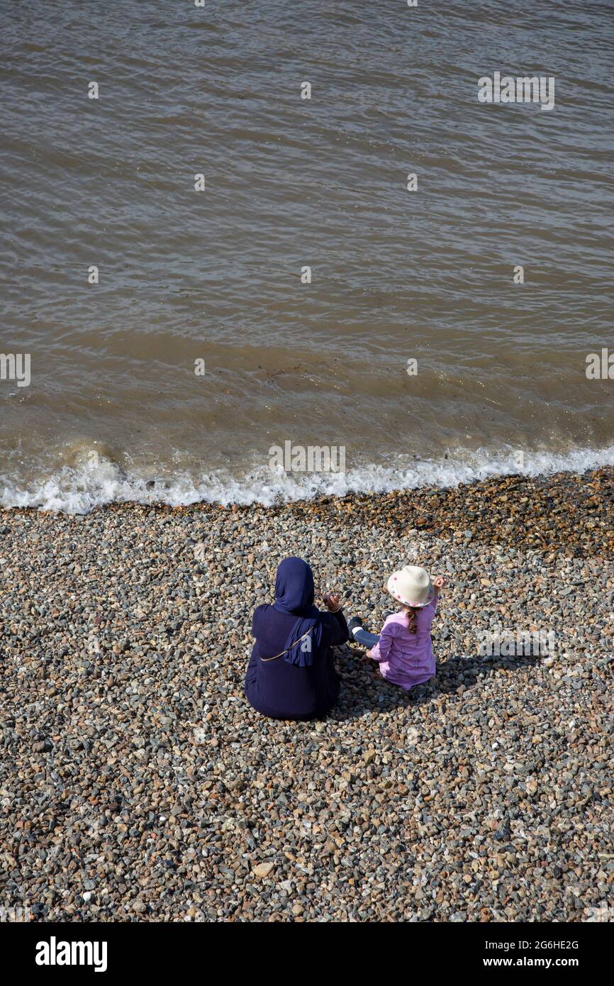 A mother and her young daughter enjoying the sunny weather on the Thames Beach on the river's south bank. London, England, UK Stock Photo