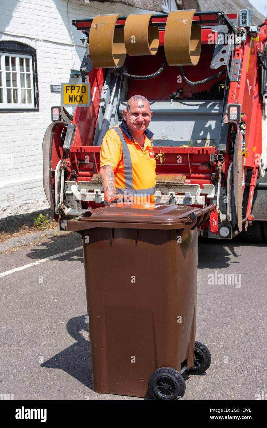 Hampshire, England, UK. 2021. Contractor returning garden waste bin to households after being