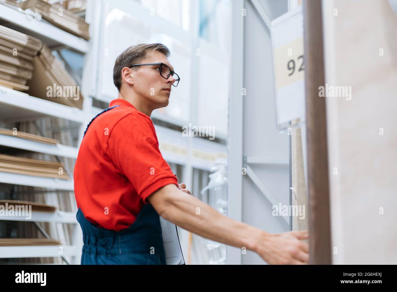 employee of a flooring store standing near the shelves with a laminated