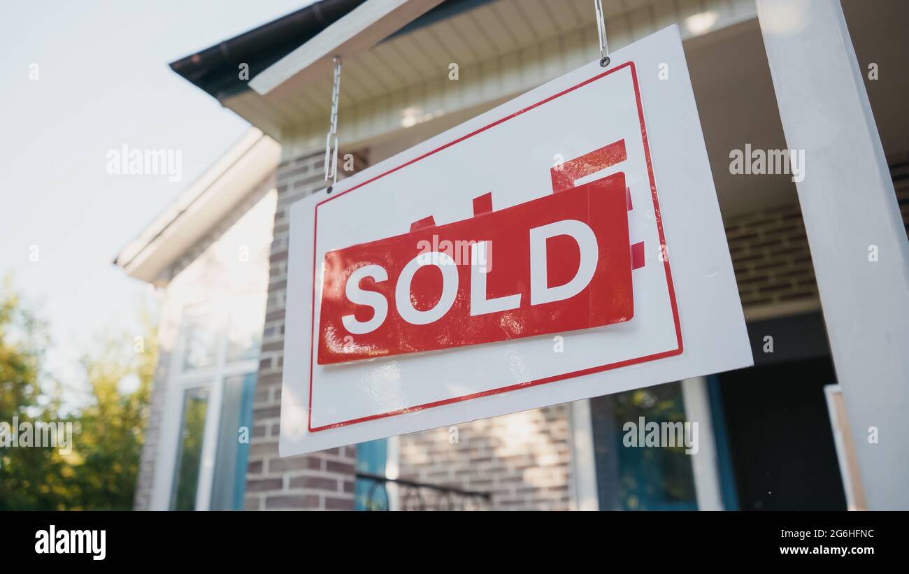 sticky label with sold lettering on board near modern house Stock Photo