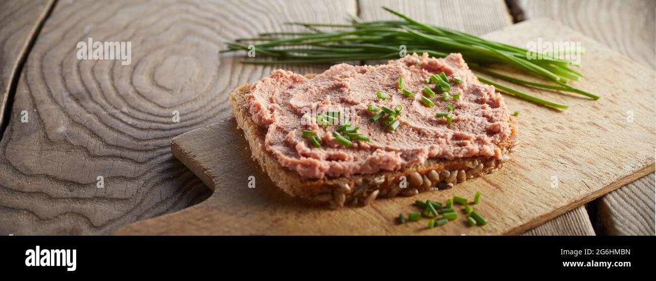 High angle of nutritious open sandwich with liver pate and green onion served on wooden table Stock Photo