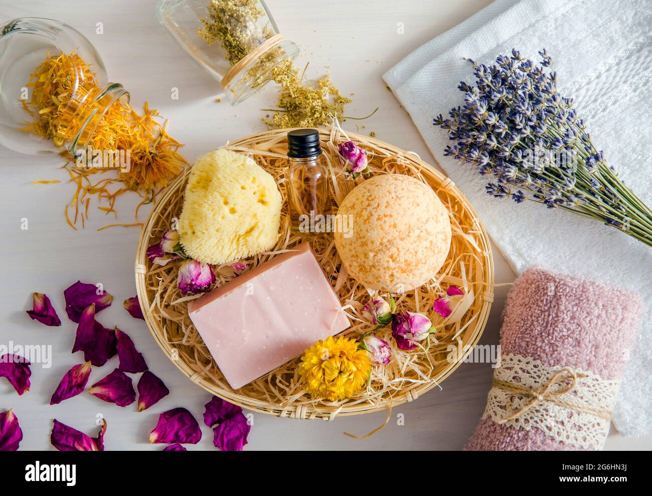 Different natural dried herbs flower petals used in beauty bath products concept. Top view of bath bomb, natural sea sponge, bar of soap, aroma oil bo Stock Photo
