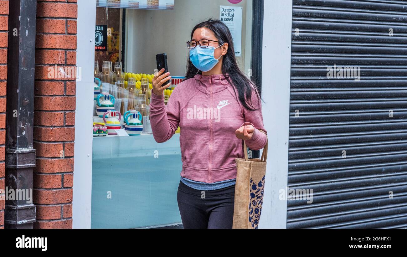 A young lady concentrates on her phone on a shopping expedition in Belfast's Castle Lane Stock Photo