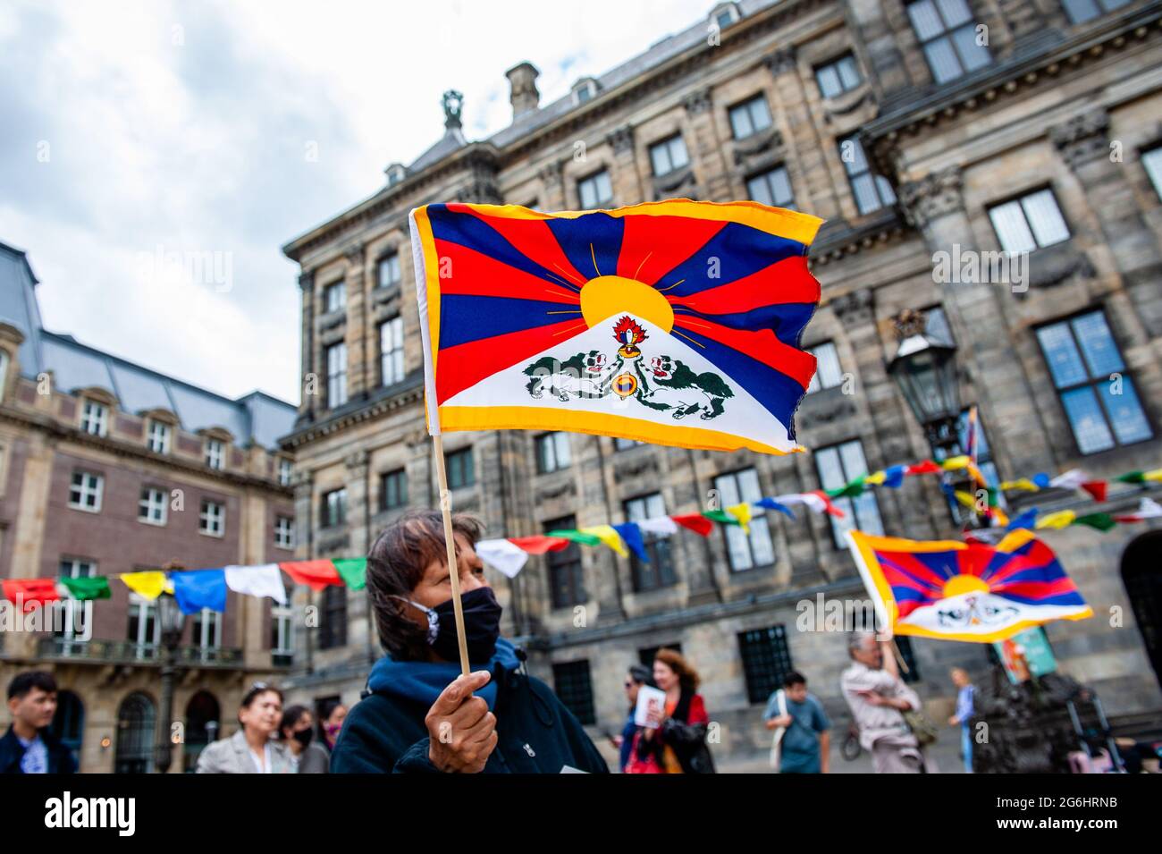 Amsterdam, Netherlands. 06th July, 2021. A Tibetan woman holding a Tibetan flag, during the celebration. To celebrate Dalai Lama's 86th birthday, and his decades of work for human rights, justice, and peace, a big event was organized in Amsterdam. Hundreds of people gathered at the Dam square in the center of the city that was decorated with colorful Tibetan flags. During the celebration a Sangsol ceremony was carried out by a Tibetan monk, and to end the ceremony a traditional Tibetan dance was performed by the Tibetan community in the Netherlands. Credit: SOPA Images Limited/Alamy Live News Stock Photo